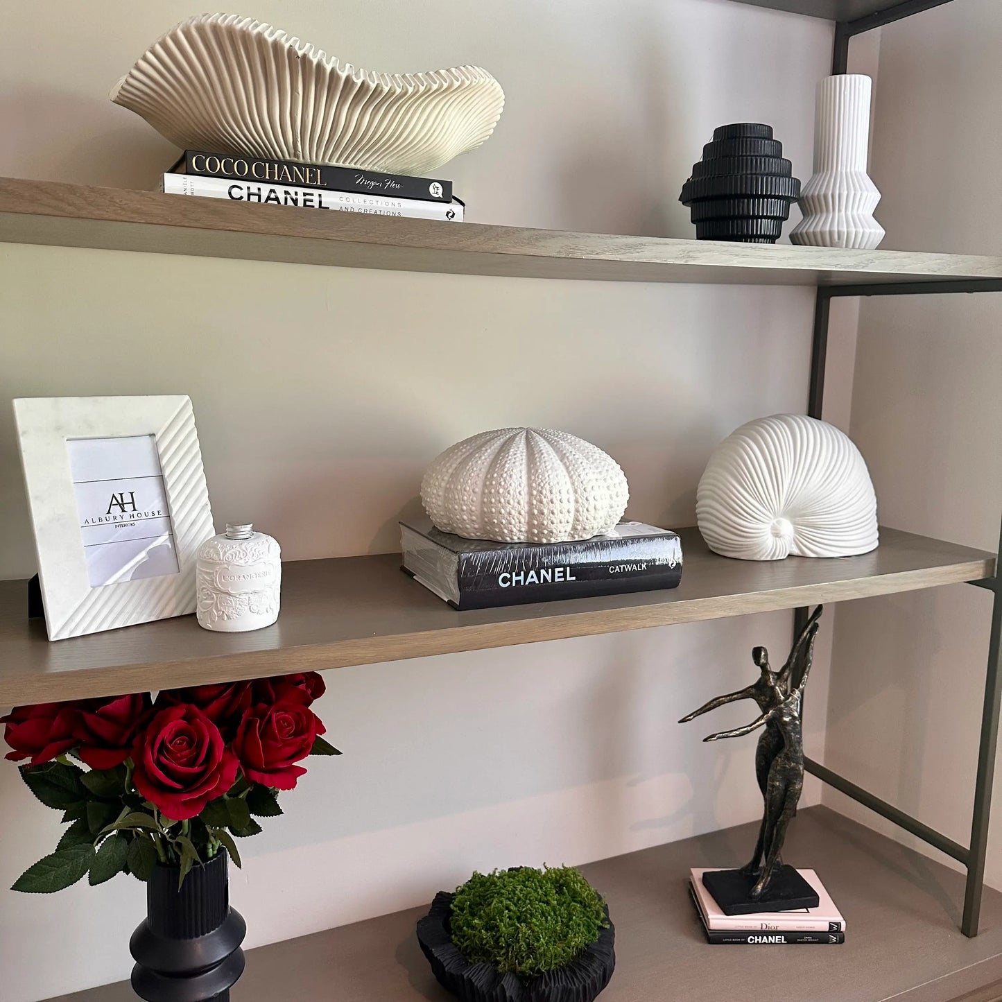 bespoke-media-unit-made-by-chordal-green-displaing-white-ceramic-snail-shell-sculpture-designer-coffee-table-books-cream-wave-bowl-red-roses-monochrome-vases-photoframe-diffuser-at-albury-house-interiors-essex