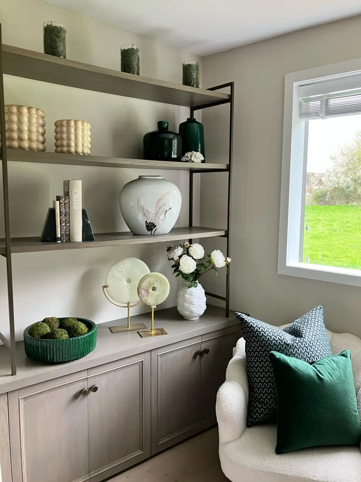 bespoke-shelving-unit-with-walnut-shelves-and-antique-bronze-ladders-displaying-vases-plant-pots-disc-sculptures-and-books-from-albury-house-interiors