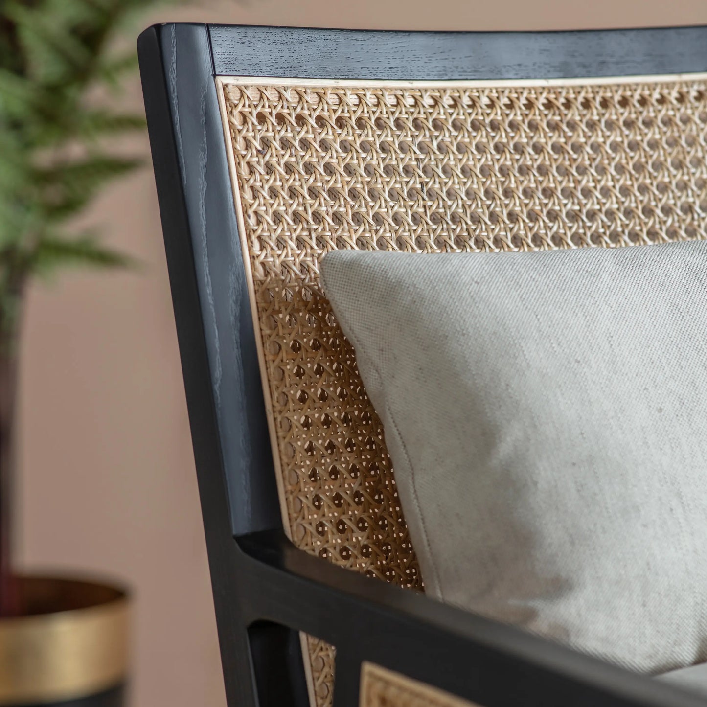 Rattan armchair with black wooden frame and natural coloured rattan, includes a neutral seat cushion and back cushion. Available at Albury House Interiors Essex.