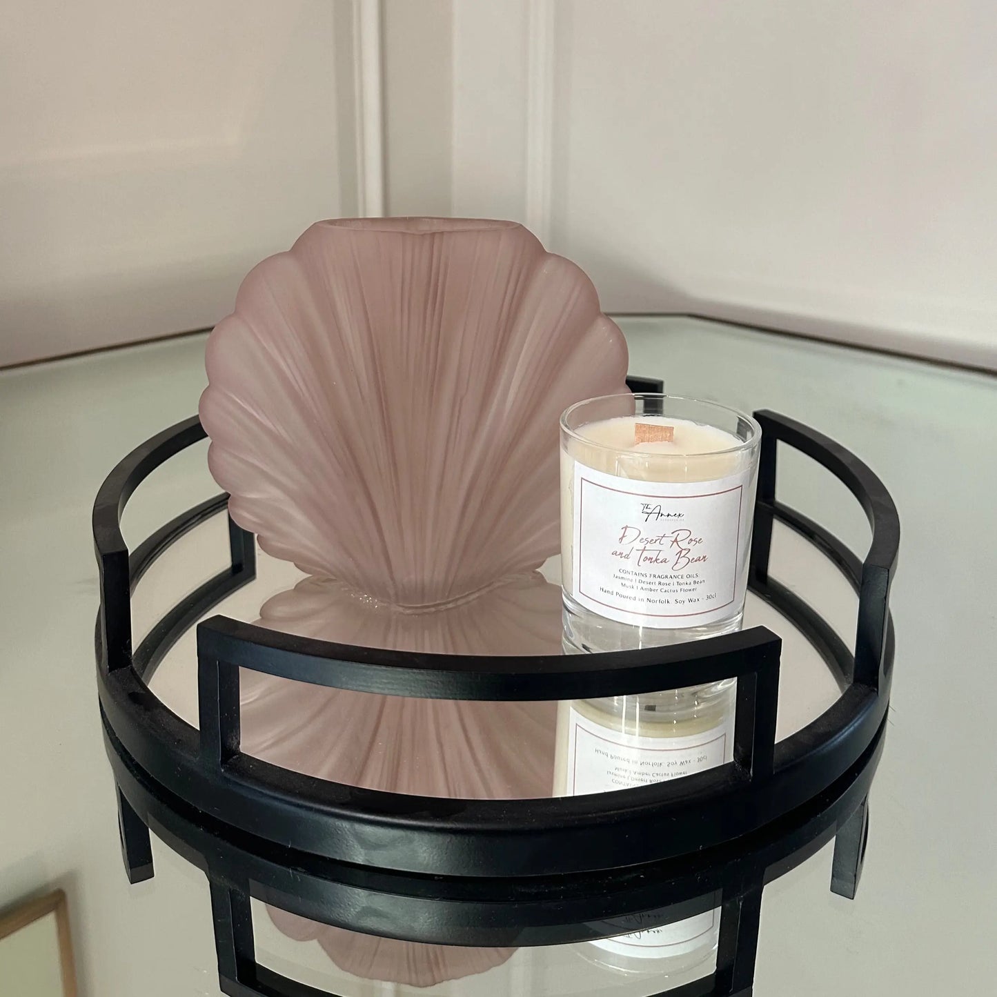 blush-pink-glass-shell-shaped-vase-and-white-desert-rose-and-tonka-bean-natural-candle-on-black-mirror-round-cruz-tray-at-albury-house-interiors