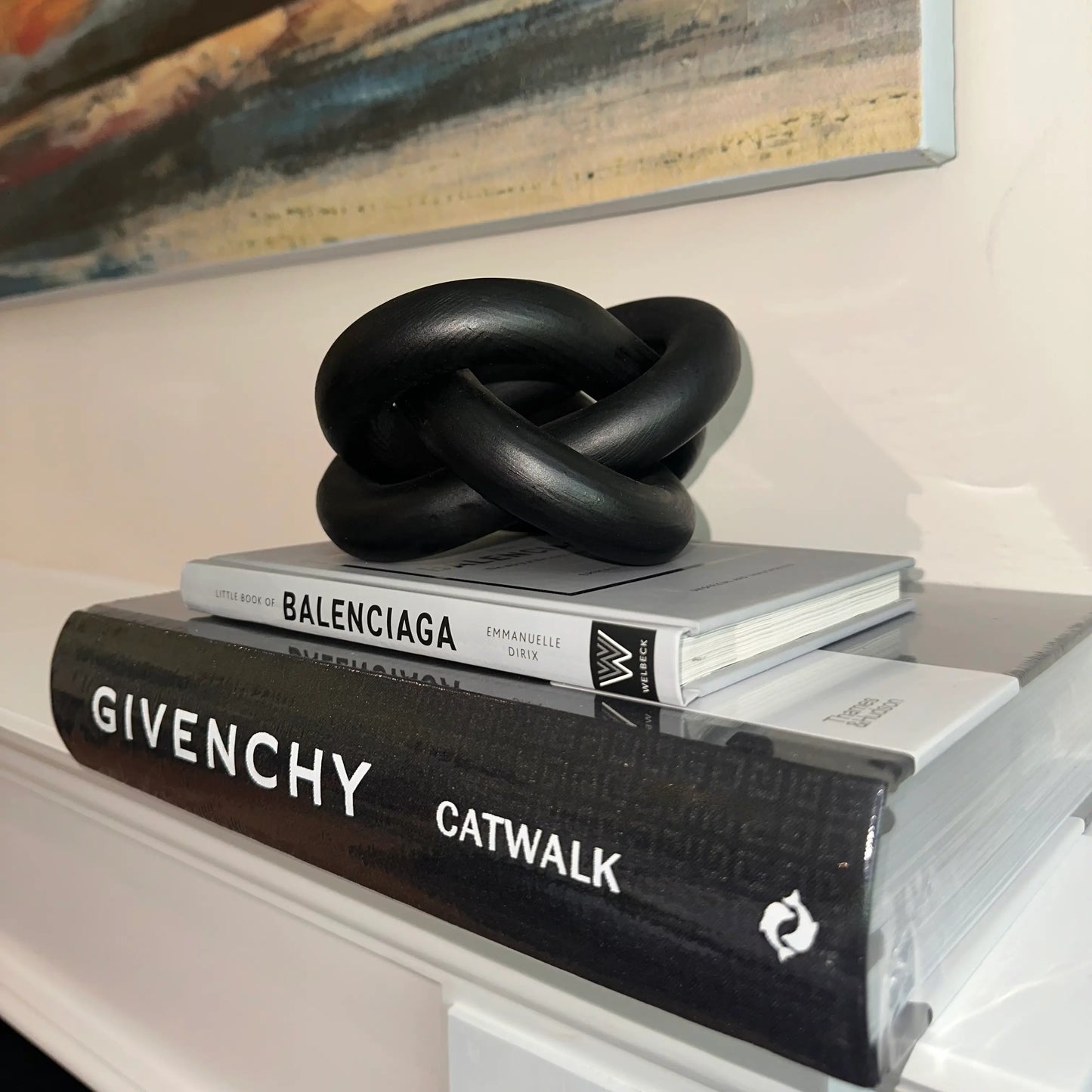 Black patterned Givenchy Catwalk book paired with the Little Book of Balenciaga and a black knotted sculpture, placed on mantelpiece. Available to purchase from Albury House Interiors.