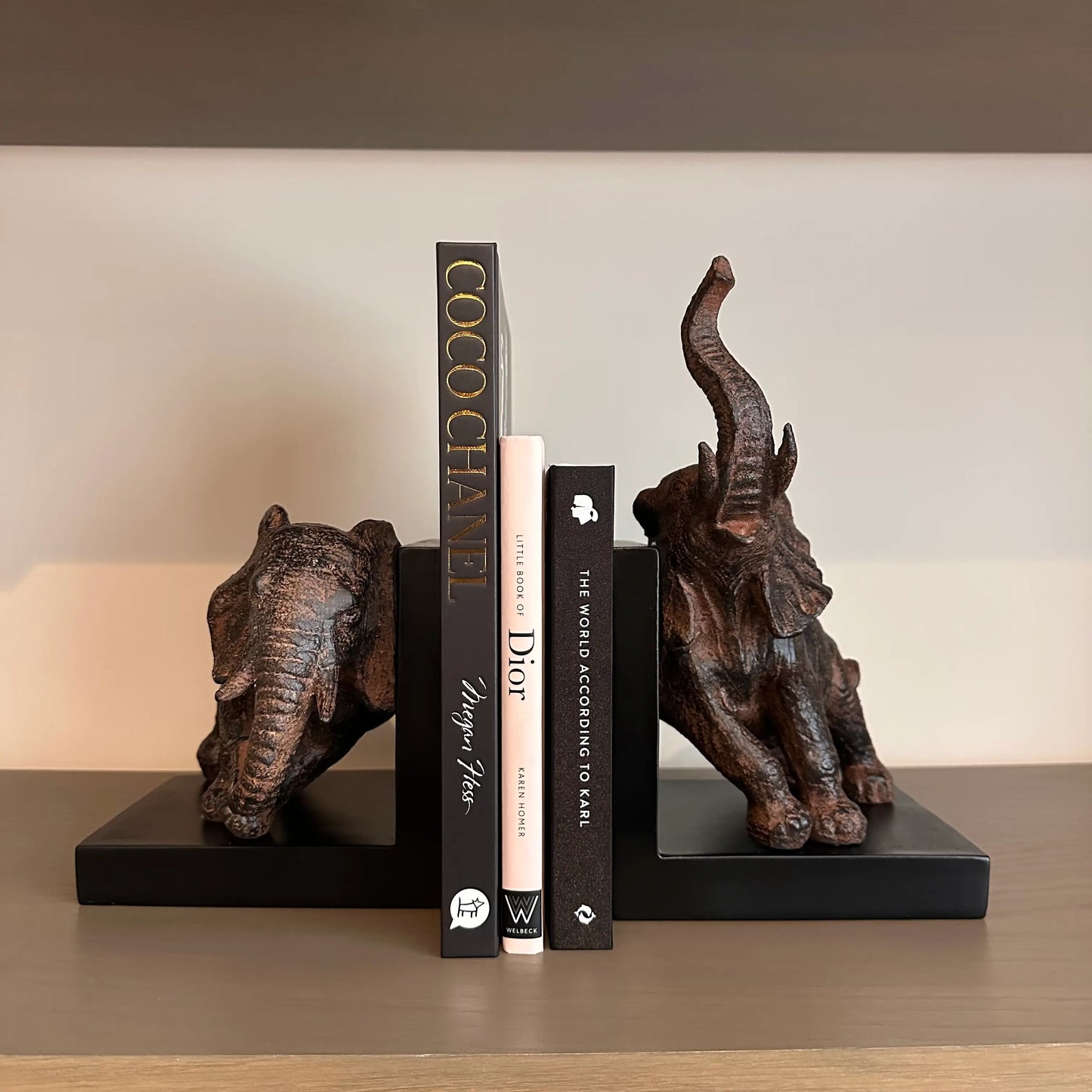 antique-bronze-and-black-pair-of-elephant-bookends-on-shelving-unit-with-chanel-and-dior-designer-books-at-albury-house-interiors