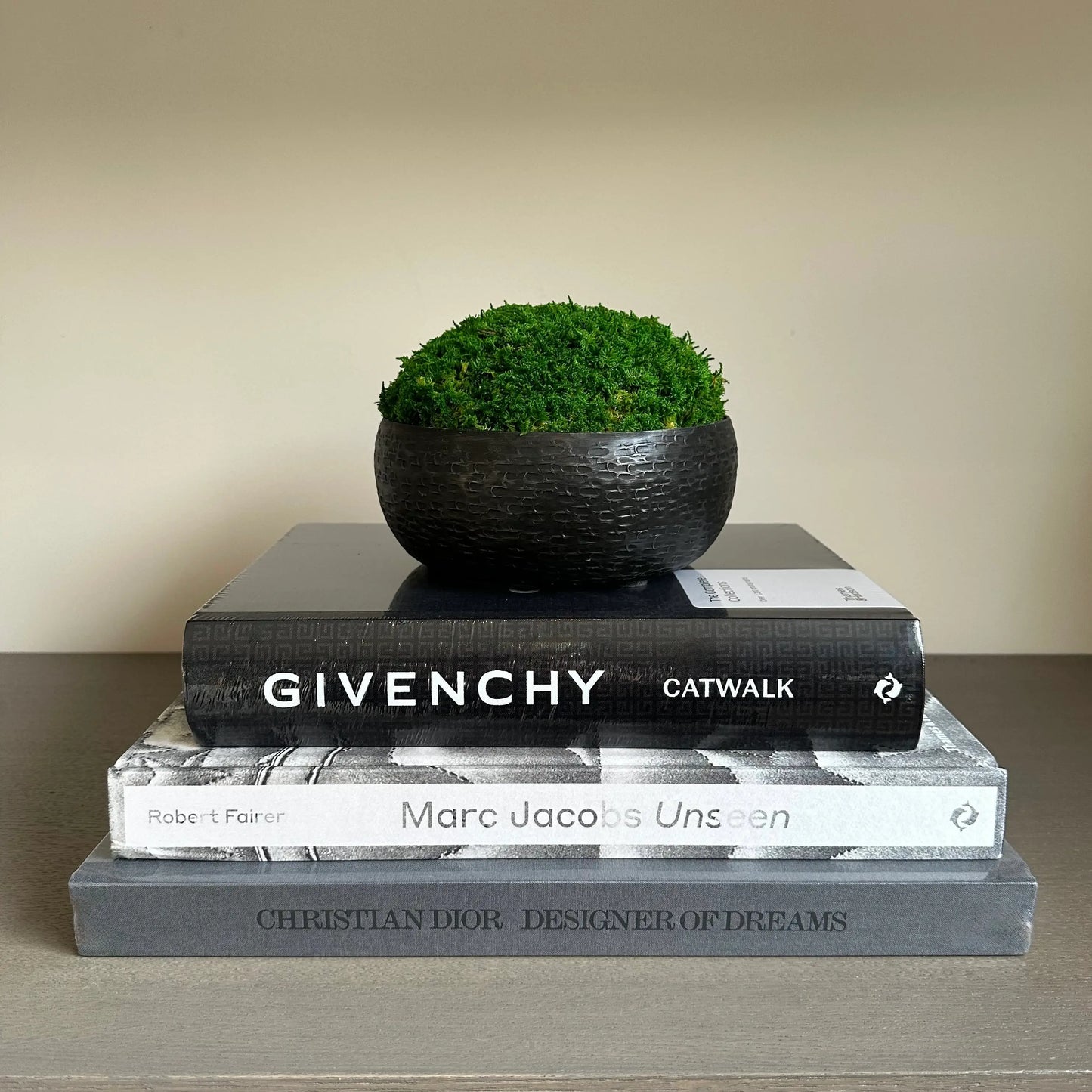 Silver grey Marc Jacobs Unseen hardback coffee table book, with stars on the front cover, back and spine. Paired with black Givenchy Catwalk book, Christian Dior Designer of Dreams book, and graphite hammered preserved moss bowl. Available to purchase from Albury House Interiors.