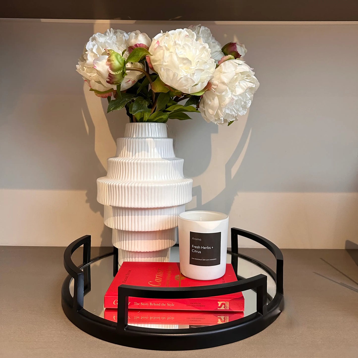 fresh-herbs-and-citrus-scented-candle-on-black-mirrored-tray-with-cartier-book-and-white-ribbed-tiered-vase-at-albury-house-interiors