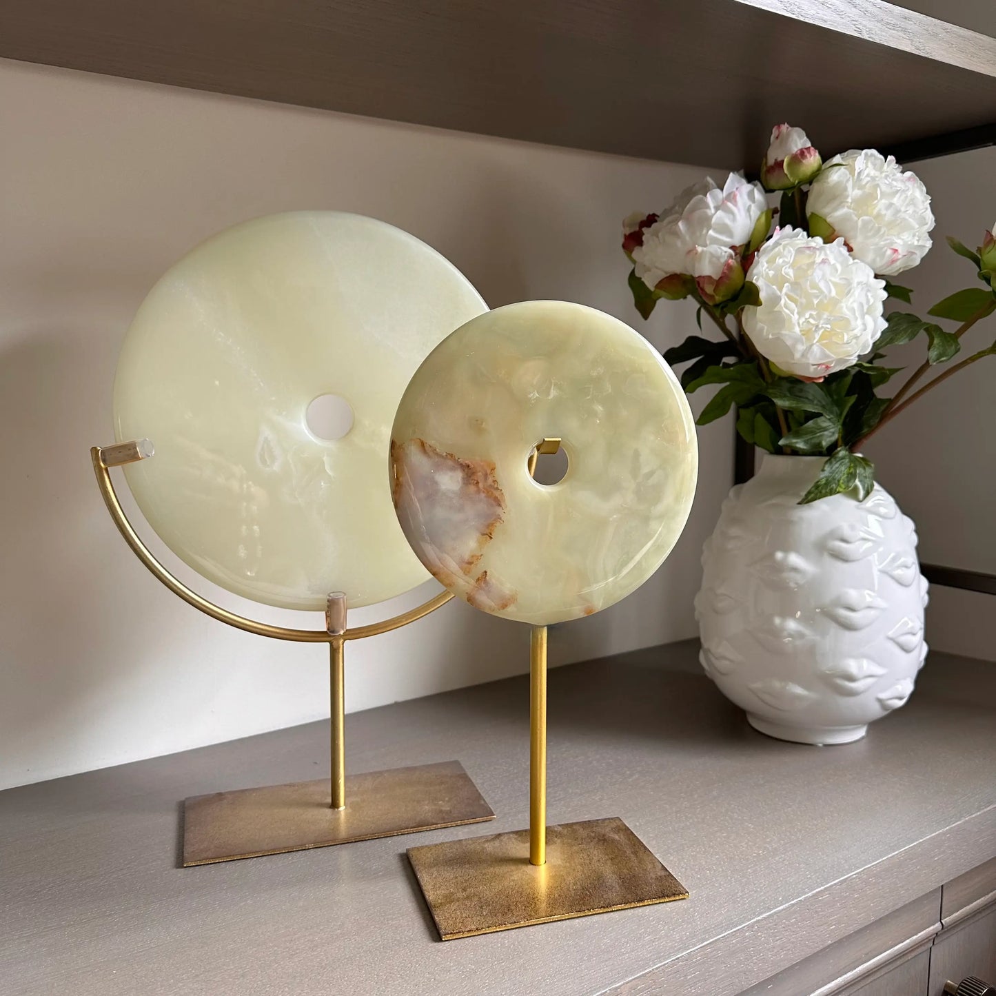 pair-of-natural-green-jade-stone-round-discs-on-distressed-gold-stands-with-white-ceramic-lip-vases-at-albury-house-interiors-essex