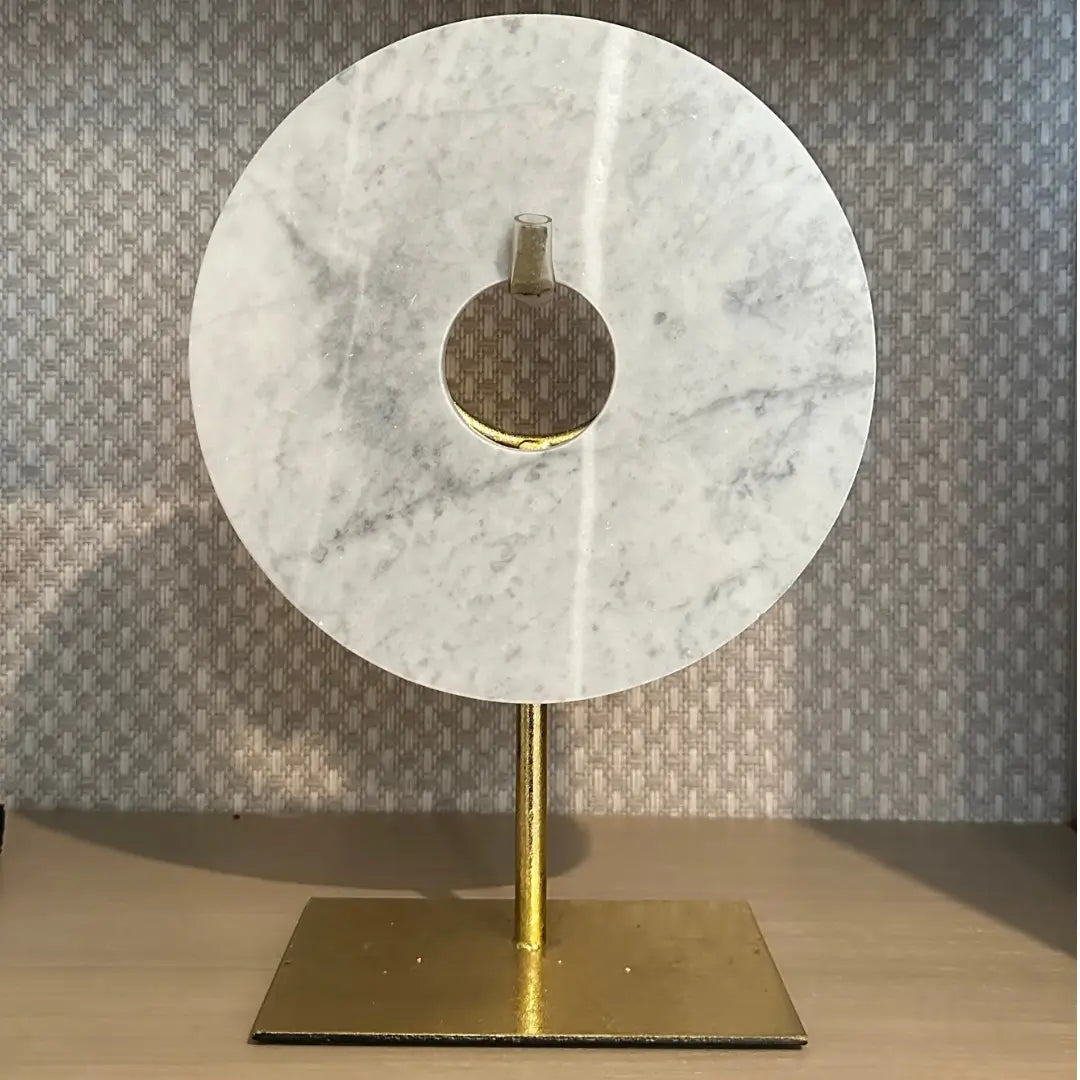 Round marble white and grey disc placed on gold stand, as used by interior designers. Available to purchase from Albury House Interiors, interior accessories in Essex and London.
