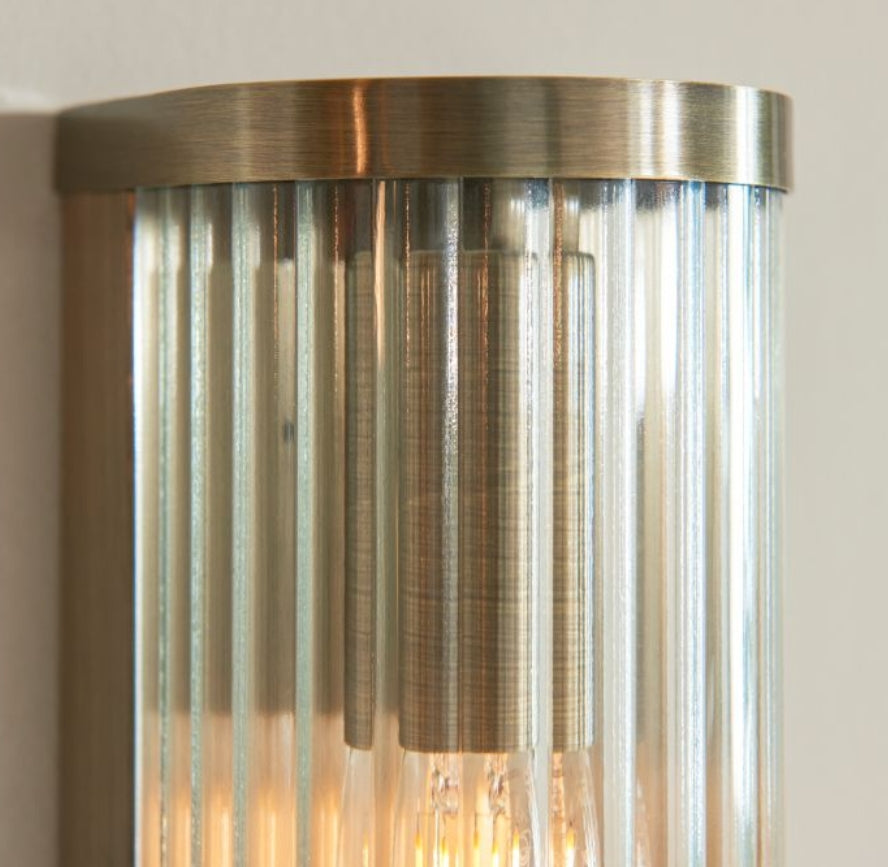Tall cylindrical wall light fixture with ribbed glass and brass fixtures. Available to purchase from Albury House Interiors.