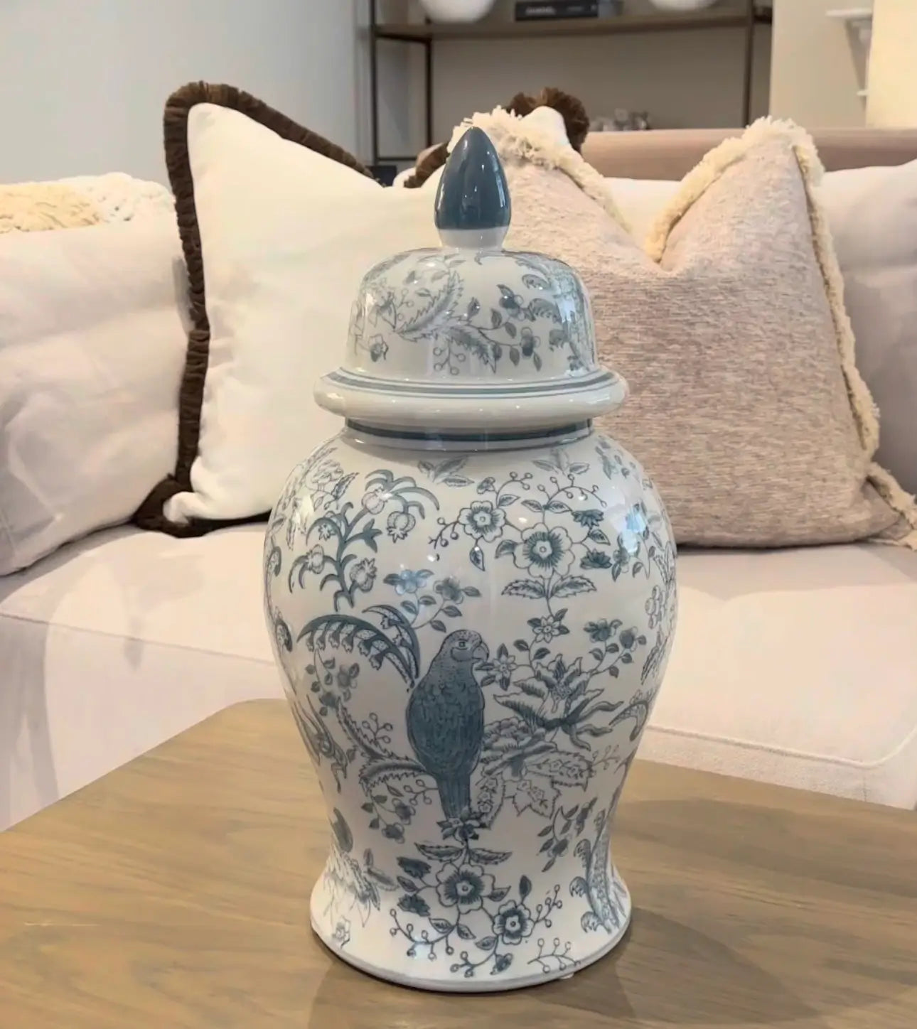 Sully square feather filled cushion with white face and reverse and thick brown fringed edge, alongside neutral boucle fringed cushion and our ceramic ginger jar with bird and flower patterns. Available to purchase from Albury House Interiors.