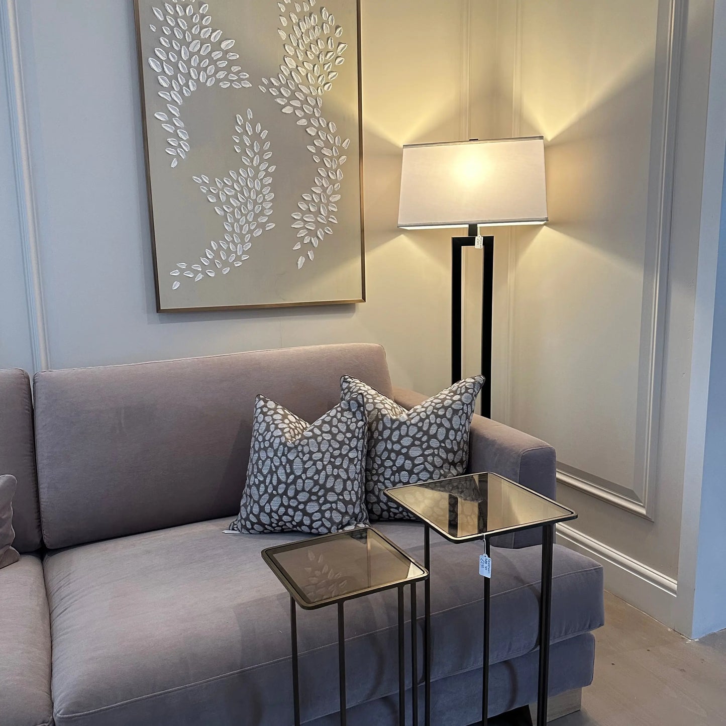 taupe-and-grey-square-piped-pebbles-patterned-cushions-on-beige-brandon-sofa-with-antique-bronze-tinted-glass-side-tables-and-lack-and-white-balmoral-lamp-at-albury-house-interiors-essex