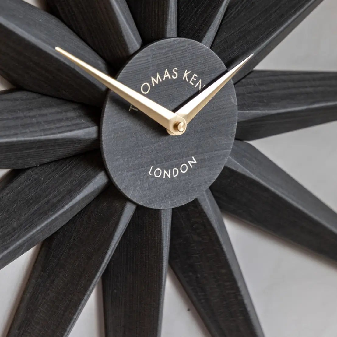 Starburst statement wall clock in North Star shape crafted from wood and finished in a dark warm grey, with gold accents and matching clock hands. Available to purchase from Albury House Interiors, home decor and accessories shop in Essex.