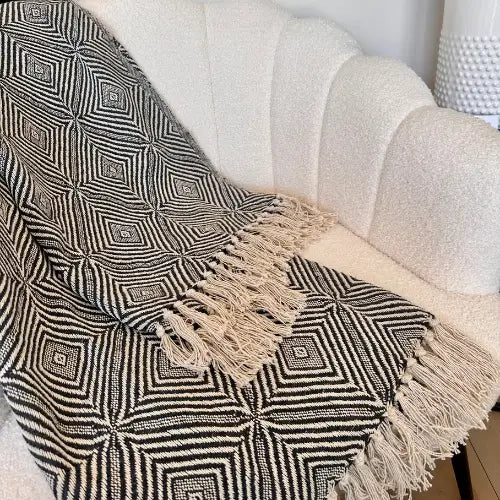 Black and white retro paisley print throw blanket crafted from recycled materials with fringed tassel edge. Available to purchase from Albury House Interiors.