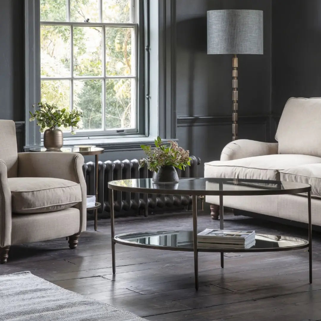 Antique bronze finish curved oval shape coffee table with glass top and mirrored bottom shelf, available at Albury House Interiors.
