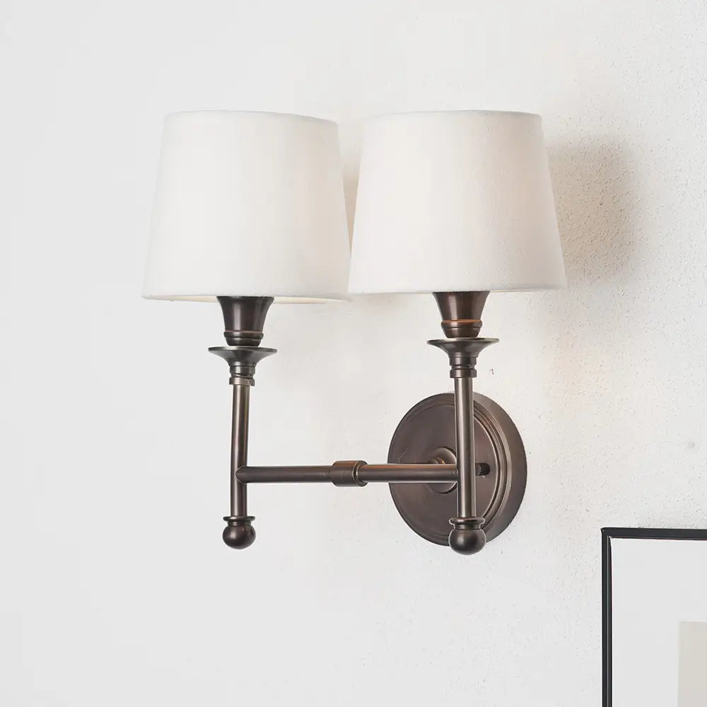 dark-antique-bronze-double-sconce-wall-light-with-white-cotton-shades-on-feature-wall-at-albury-house-interiors