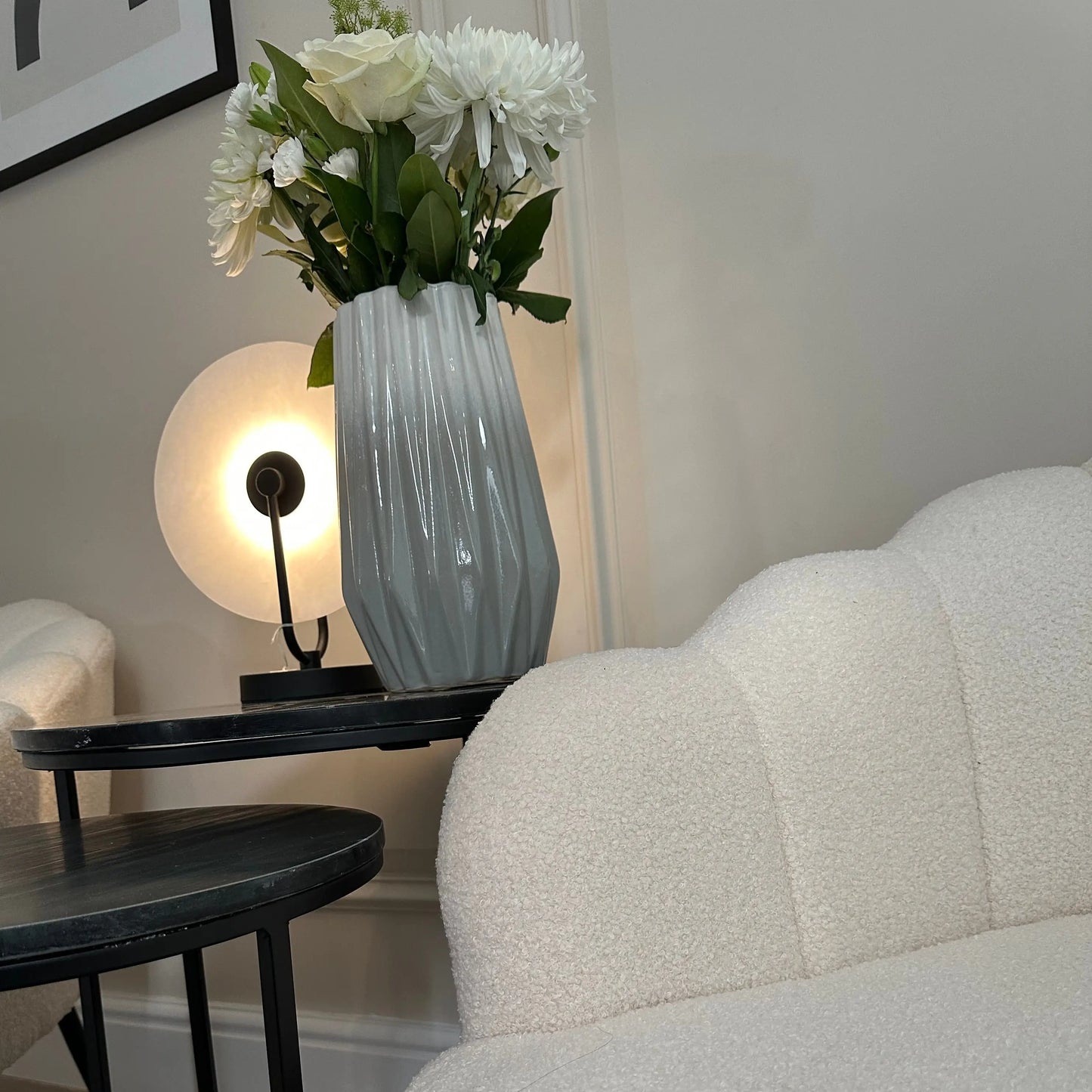 White soft boucle armchair occasion chair in a shell shape with scalloped edges and matte black legs, paired with nesting black marble side tables and marble lamp. All items available to purchase from Albury House Interiors, Essex. 