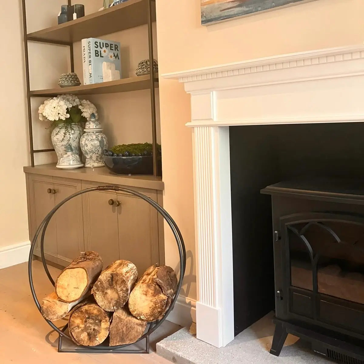 circle shaped black metal firewood holder with logs next to fireplace at albury house interiors 