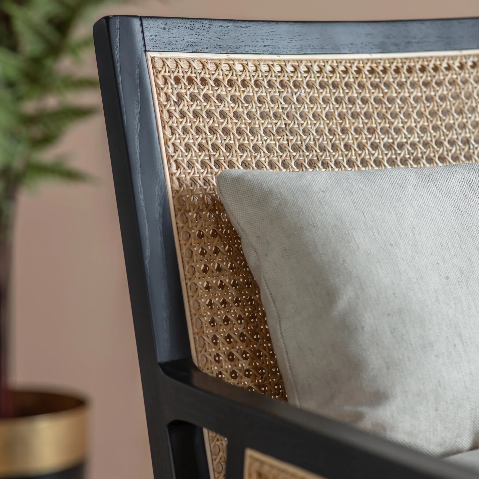 Rattan armchair with black wooden frame and natural coloured rattan, includes a neutral seat cushion and back cushion. Available at Albury House Interiors Essex.