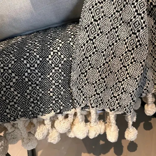 Black and white aztec patterned double sided throw, with cream pompom edges. Available to purchase from Albury House Interiors. 