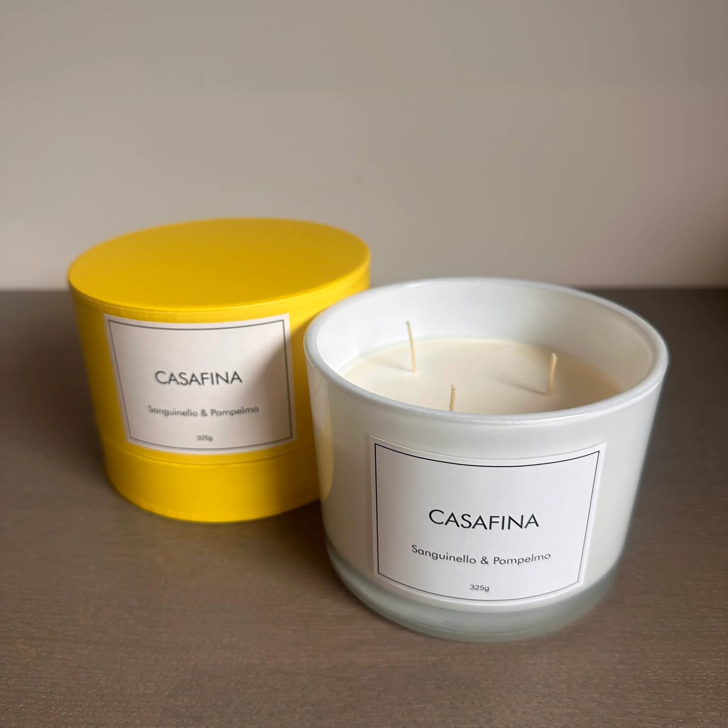 Casafina blood orange and grapefruit scented, white glass candle with three wicks, beautifully presented in a yellow gift box, available to purchase at Albury House Interiors. 
