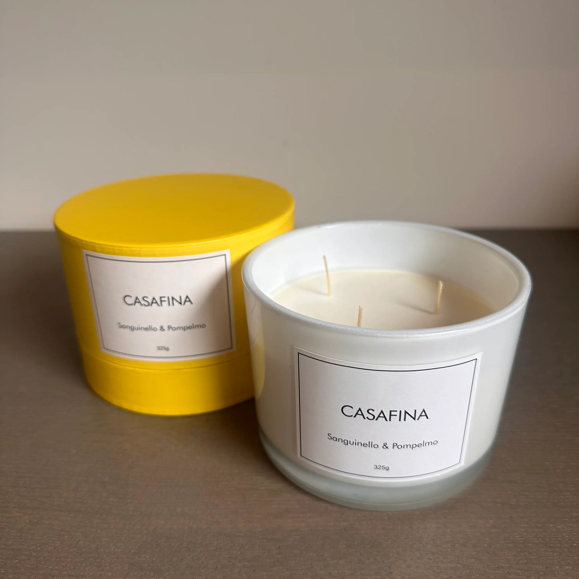 Casafina blood orange and grapefruit scented, white glass candle with three wicks, beautifully presented in a yellow gift box, available to purchase at Albury House Interiors. 