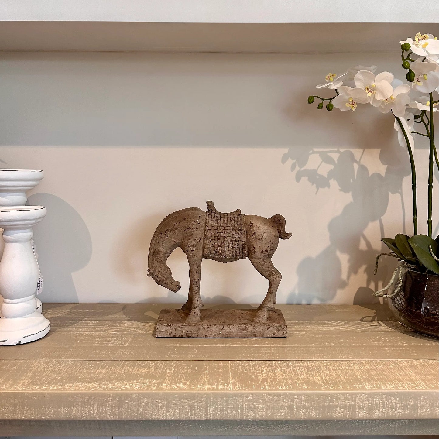 Bowing horse ornament sculpture crafted from poly resin and finished in an antique stone to give a vintage traditional look. Styled on a mango wood console table with a faux life-like orchid and white ceramic candle holders. Available to purchase from Albury House Interiors, Harlow, Essex. 