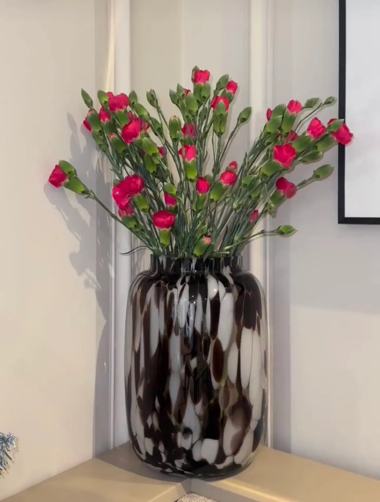Brown and white speckled mottled blown glass vase, each vase is individual as no two are the same. Styled with red carnation flowers. Available to purchase at Albury House Interiors, Essex. 