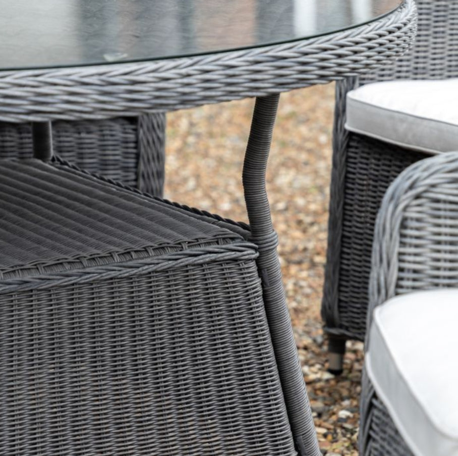 A 5-piece outdoor dining set featuring a round glass-top table and four high-back grey woven wicker chairs with white seat cushions, shown against a plain white background available at Albury House Interiors.