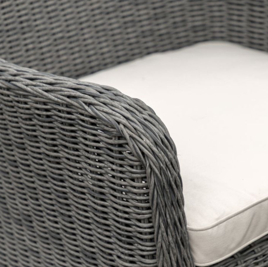A 7-piece outdoor dining set featuring a round glass-top table and six grey woven wicker armchairs, shown against a plain white background. Available at Albury House Interiors.