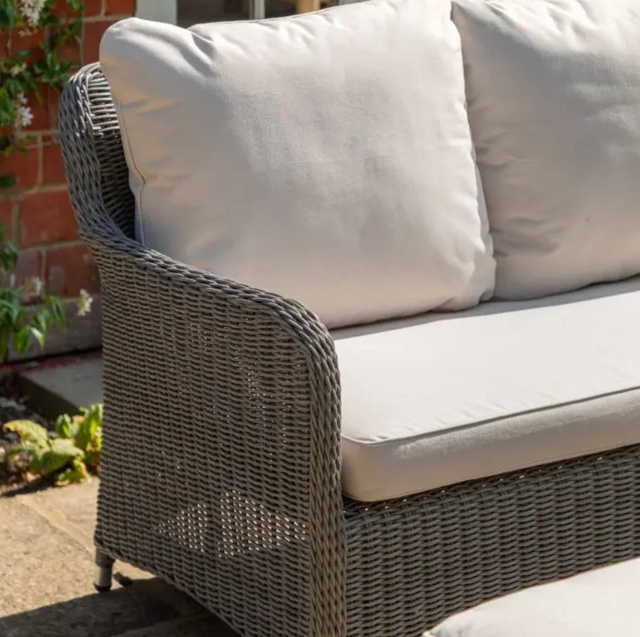 A 5-piece outdoor patio set featuring a grey wicker sectional sofa with cream cushions, a matching rectangular rising coffee table, and two ottomans on a solid white background.