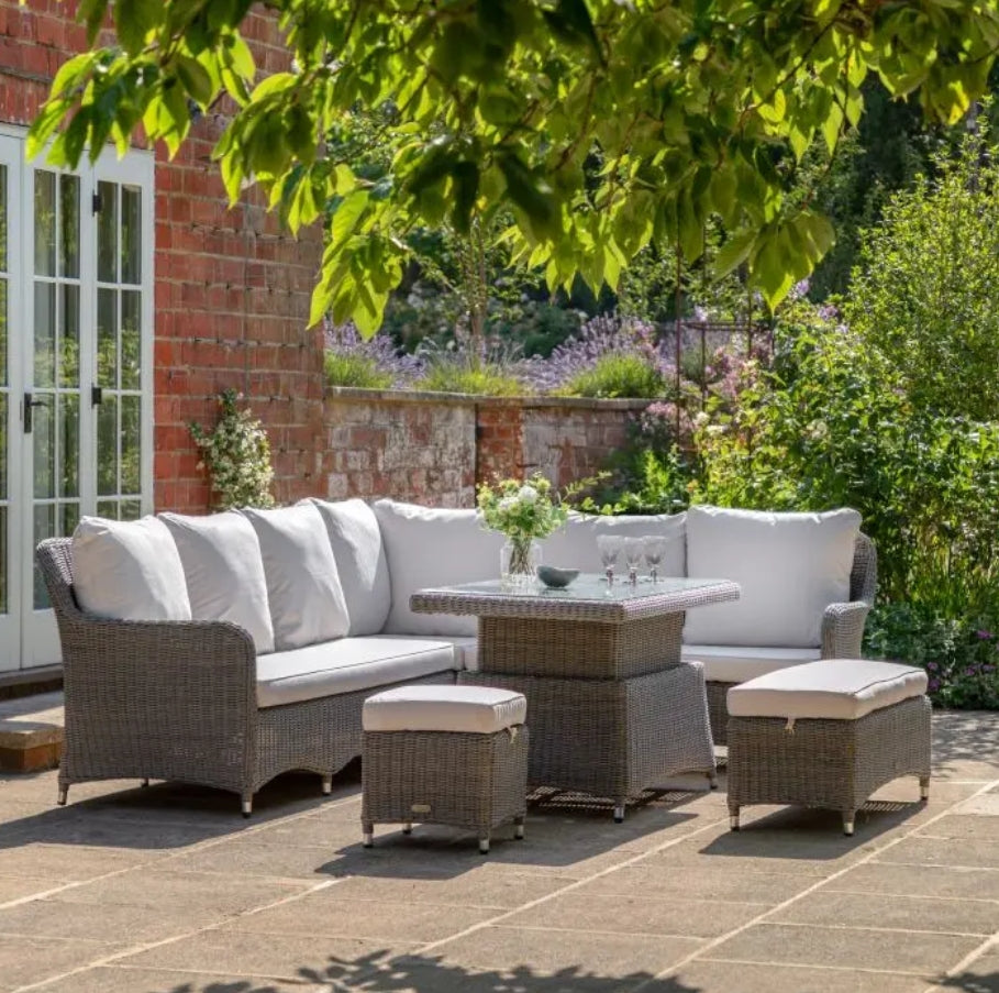 A 5-piece outdoor patio set featuring a grey wicker sectional sofa with cream cushions, a matching rectangular rising coffee table, and two ottomans on a solid white background.