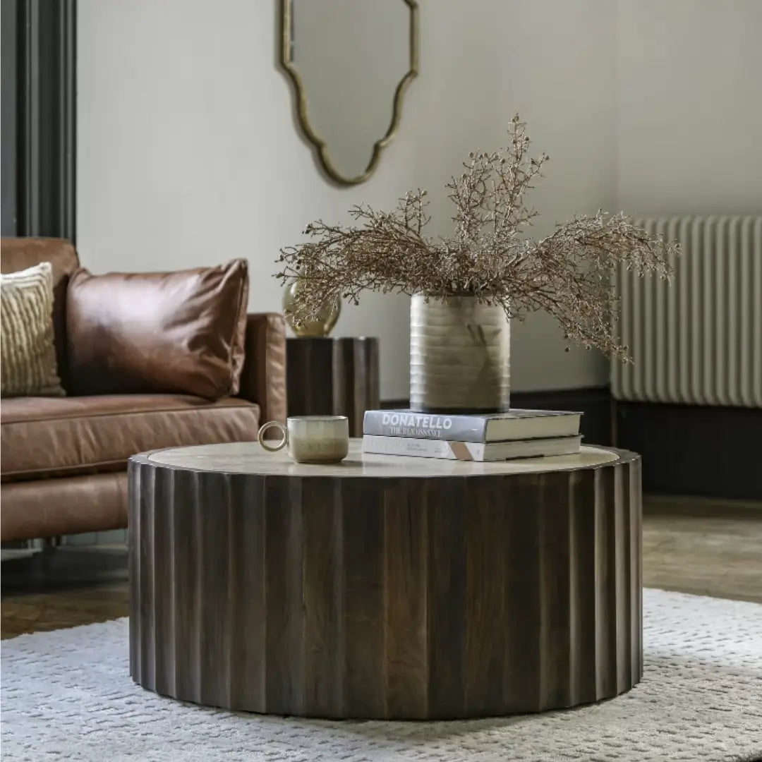 Cisca round coffee table with dark stained fluted base crafted from mango wood, and inlaid natural travertine stone top in neutral colour. Available to purchase from Albury House Interiors. 