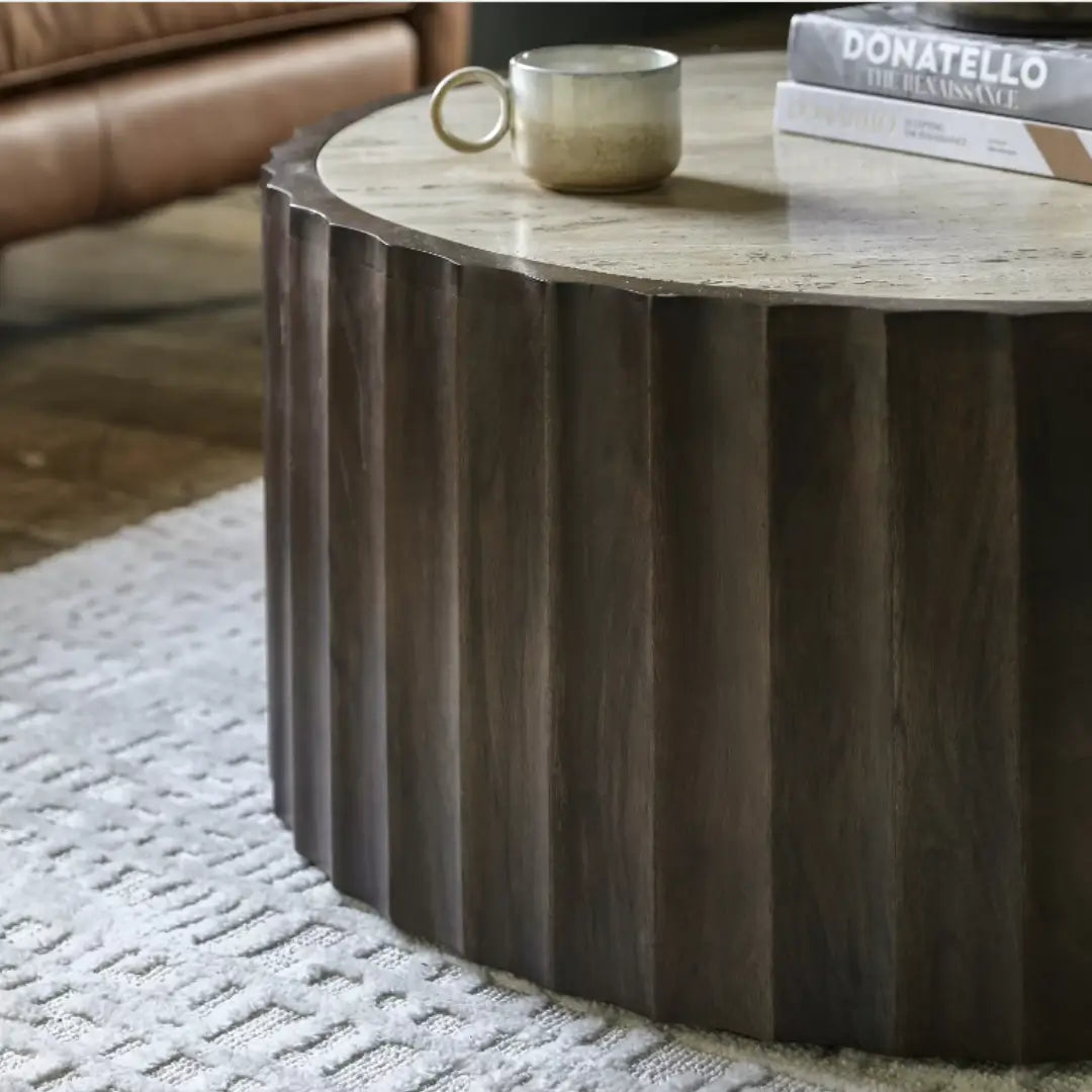 Cisca round coffee table with dark stained fluted base crafted from mango wood, and inlaid natural travertine stone top in neutral colour. Available to purchase from Albury House Interiors. 