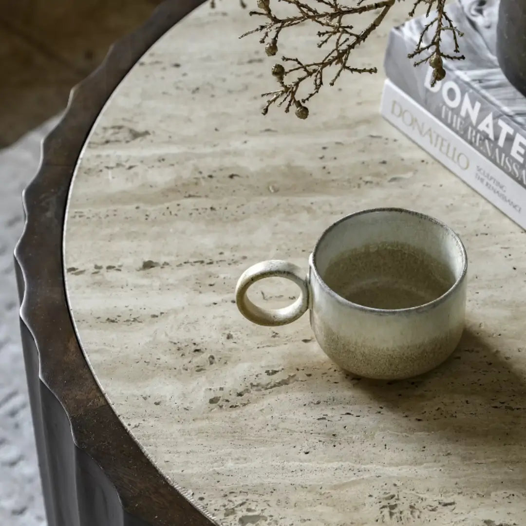 Cisca round coffee table with dark stained fluted base crafted from mango wood, and inlaid natural travertine stone top in neutral colour. Available to purchase from Albury House Interiors. 