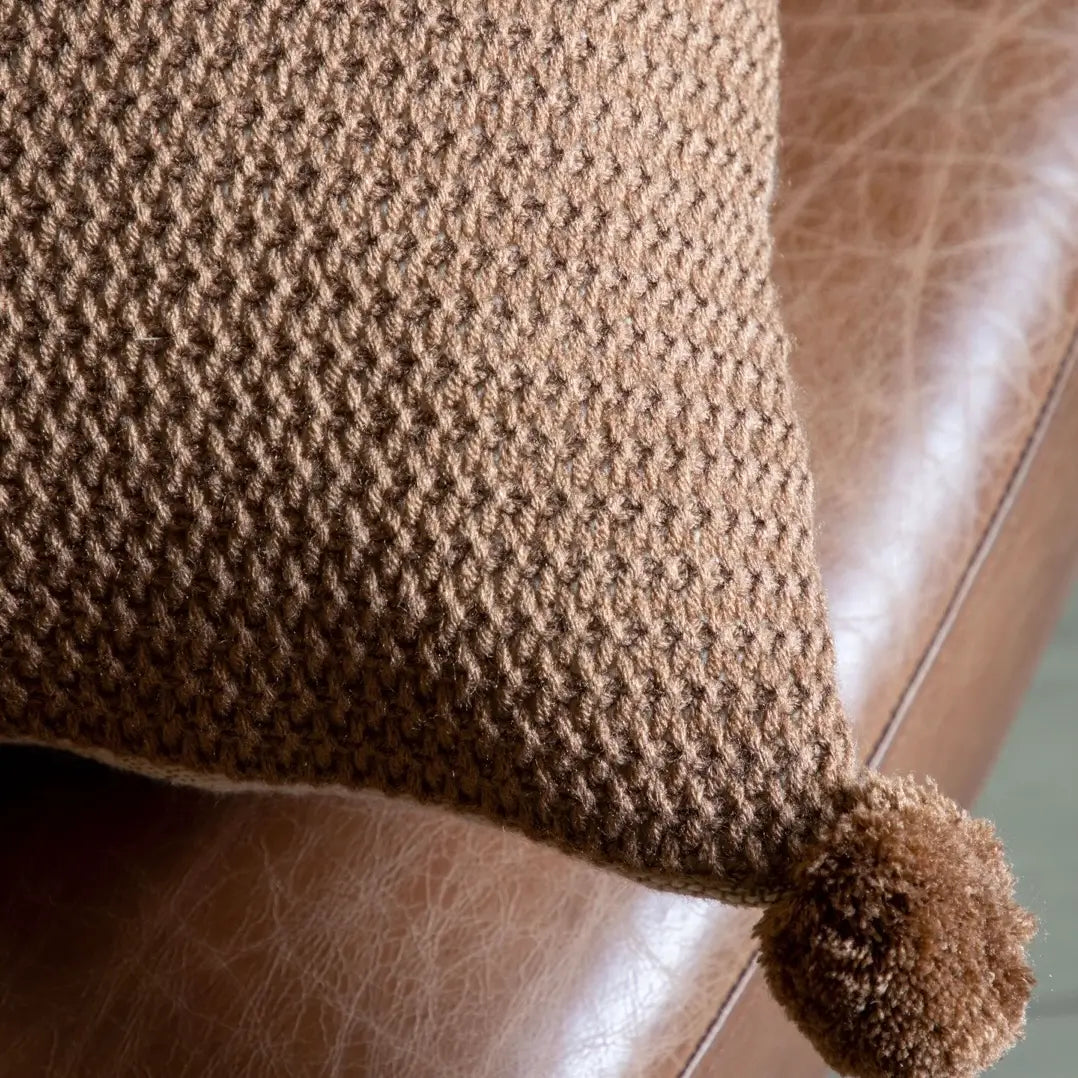 brown-knit-crochet-effect-rectangular-cushion-with-brown-pompoms-on-corners-and-neutral-colour-reverse-side-at-albury-house-interiors-essex