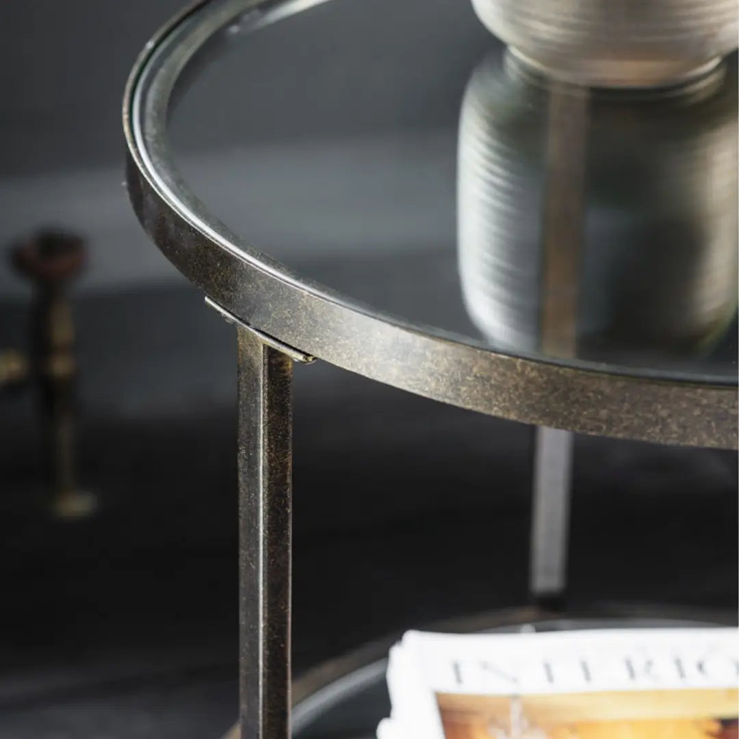 Antique bronze round side table with glass top and mirrored shelf. Perfect for use in bedrooms, living rooms, dining rooms and hallways. Available to purchase from Albury House Interiors, homewares and free standing furniture in the UK.