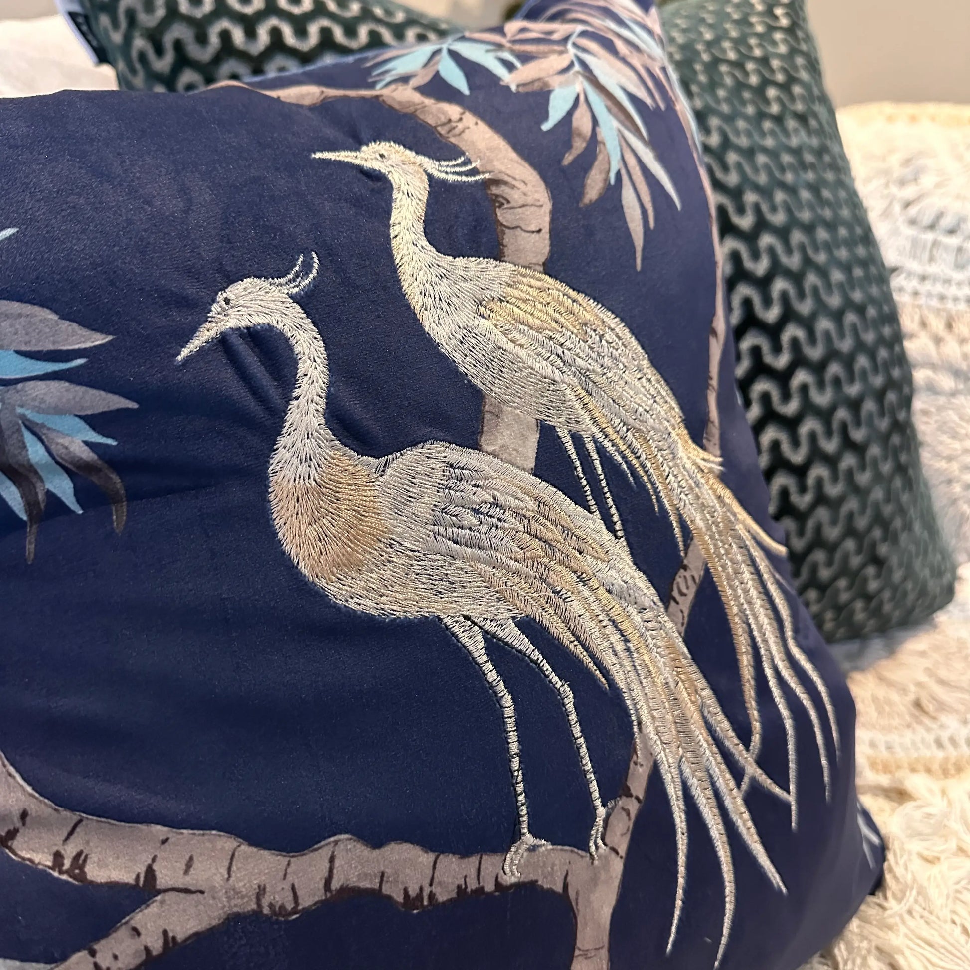 Navy blue square velvet cushion, with embroidered crane birds and delicate tree and leaf detailing, at Albury House Interiors