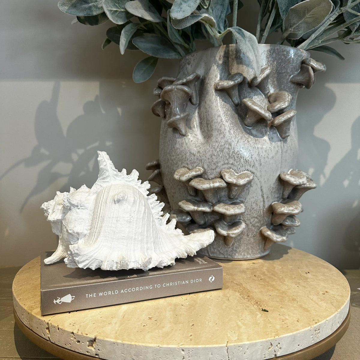 White faux conch shell ornament crafted from resin and finished in matte white, styled with our ceramic fungi vase on a stone terrazzo stray. Available to purchase from Albury House Interiors. 