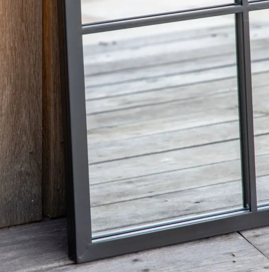A rectangular wall mirror with a black metal frame divided into a 3x4 grid of twelve square panes, shown against a decking patio background. Available at Albury House Interiors