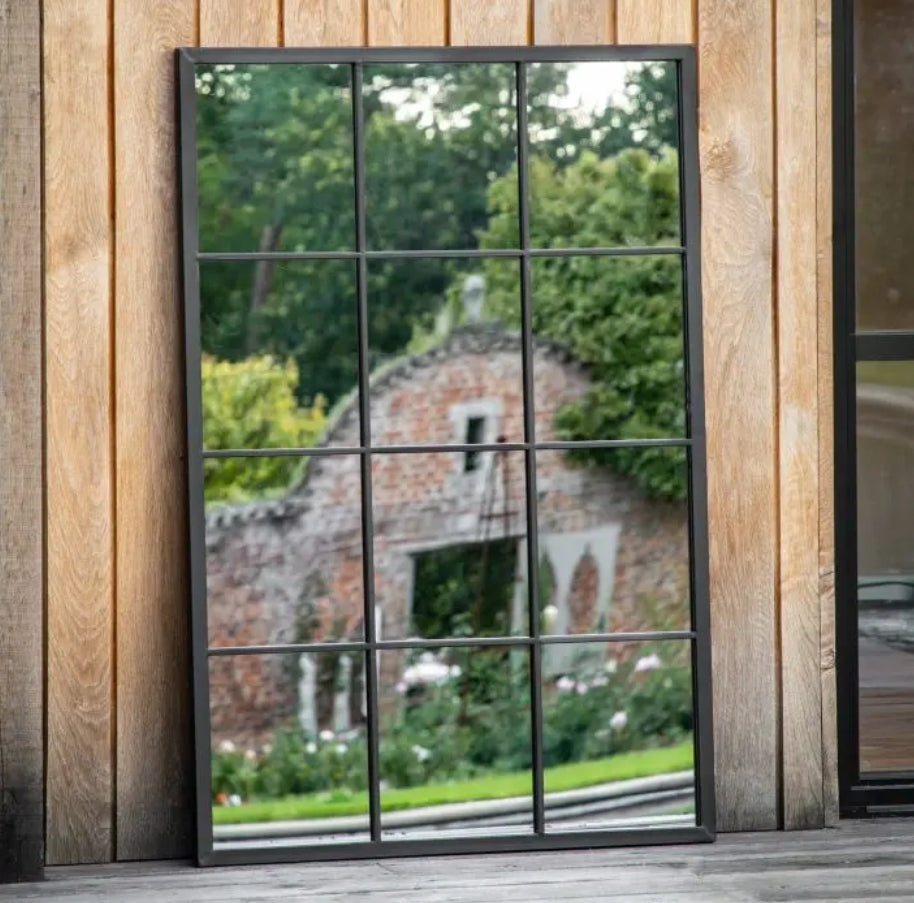 A rectangular wall mirror with a black metal frame divided into a 3x4 grid of twelve square panes, shown against a decking patio background. Available at Albury House Interiors