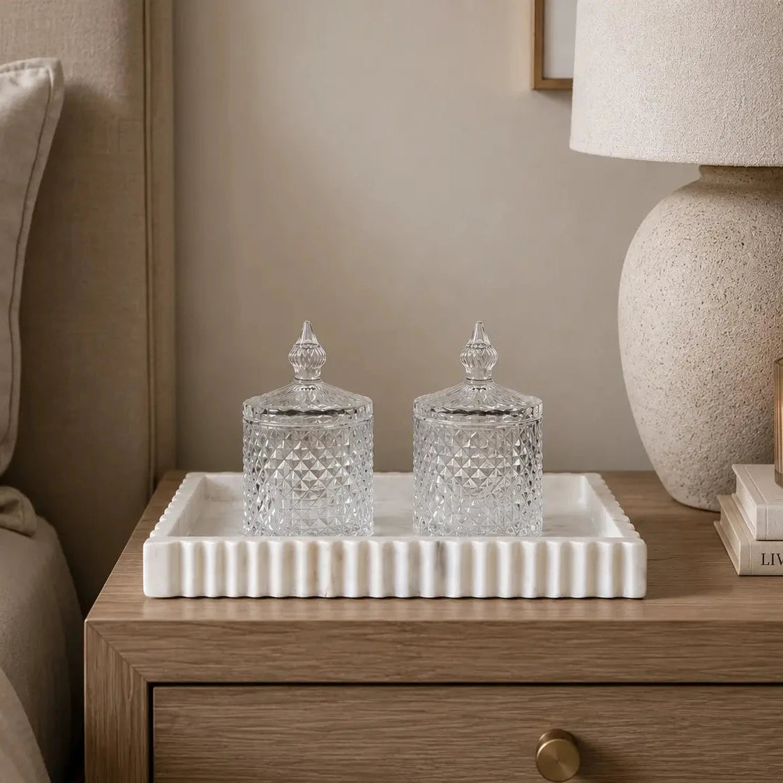 White natural marble rectangular tray with fluted edge detail, and veined pattern throughout. Displayed here on an oak bedside table with two cut glass lidded  jars. Available to purchase from Albury House Interiors.
