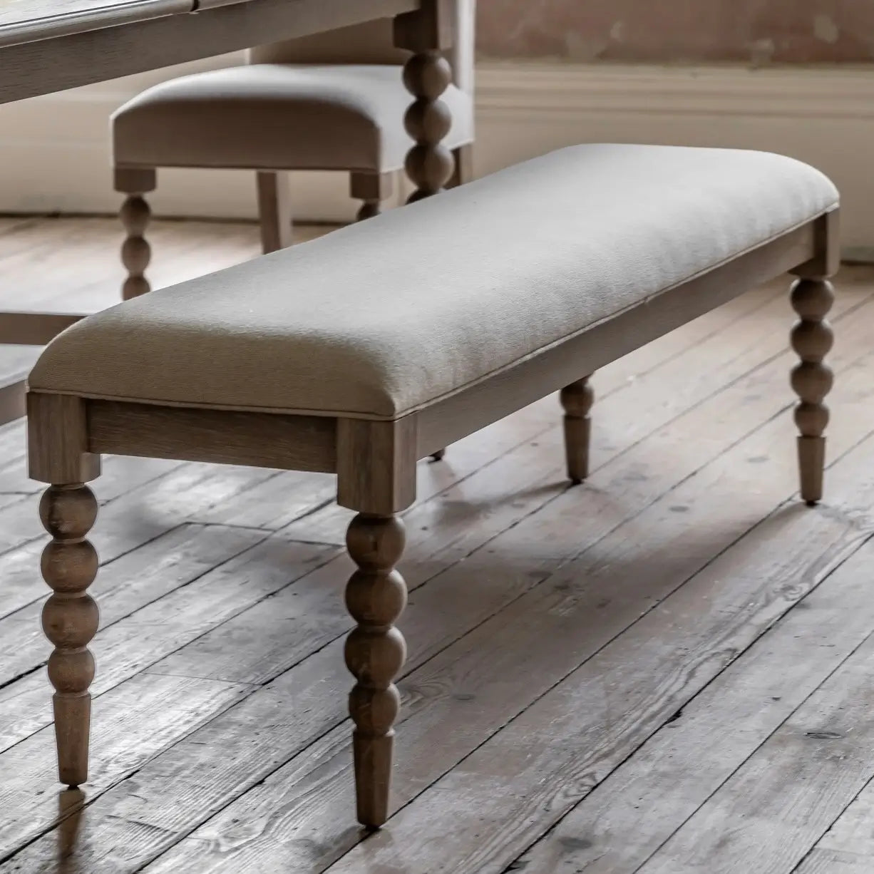 lime-washed-oak-dining-bench-bobbin-round-detailed-legs-with-biscuit-neutral-fabric-upholstery-at-albury-house-interiors-giftware-and-homeware-shop-in-essex