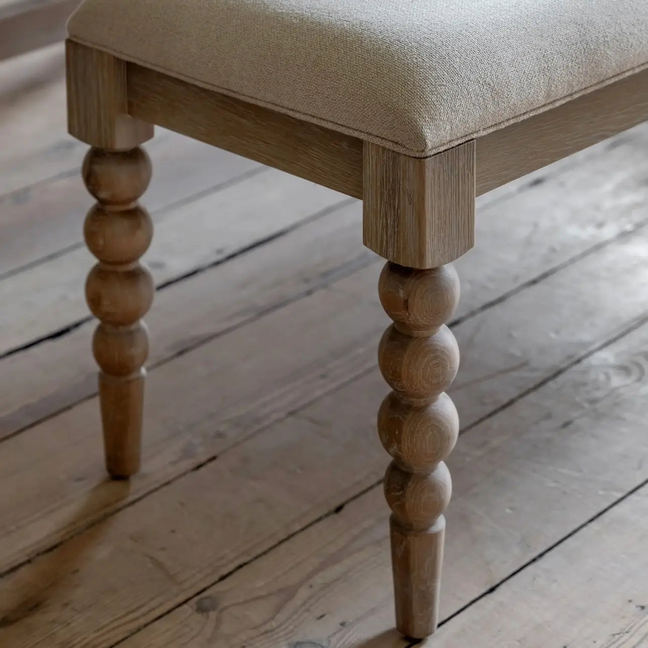 lime-washed-oak-dining-bench-bobbin-round-detailed-legs-with-biscuit-neutral-fabric-upholstery-at-albury-house-interiors-giftware-and-homeware-shop-in-essex