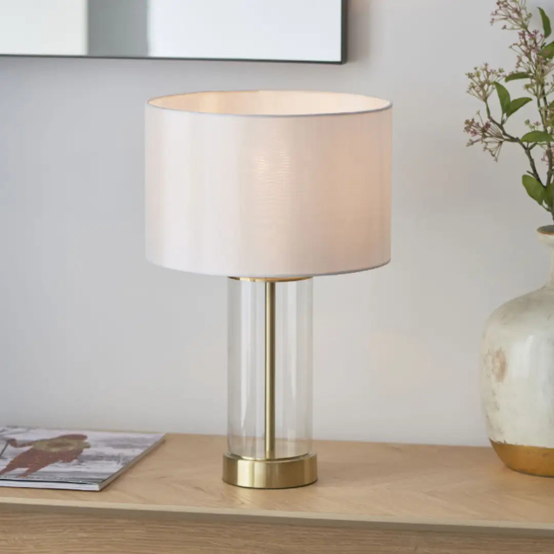 Louvre glass cylinder table lamp with brushed gold accents, complete with white faux silk round lampshade, available at Albury House Interiors, homewares shop in Essex. 