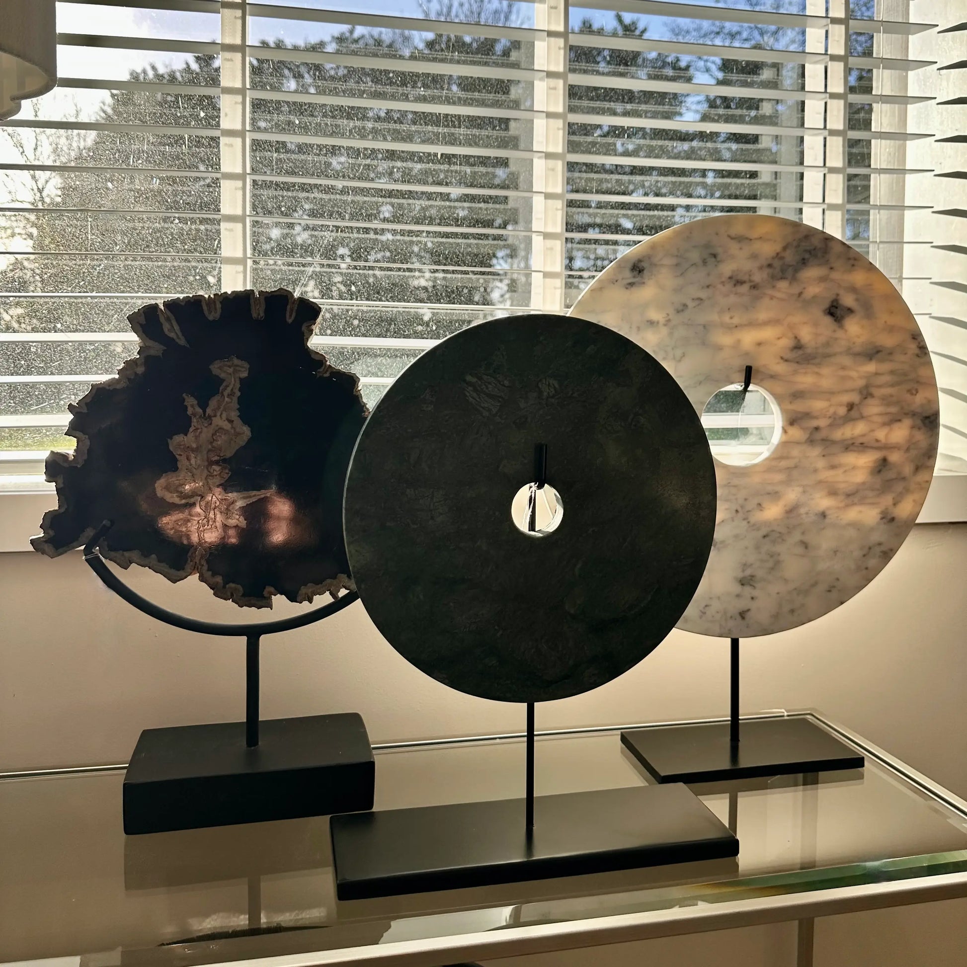 white-and-green-marble-discs-and-petrified-wood-sculpture-on-matt-black-stands-at-albury-house-interiors