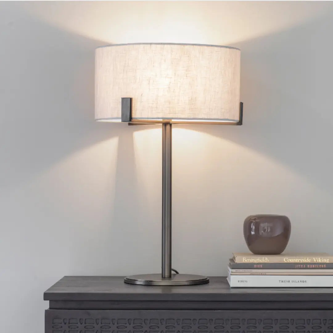 Minnesota table lamp with dark brushed brass base and metal features, and round natural linen lampshade. Available to purchase at Albury House Interiors, luxury homewares in the UK.