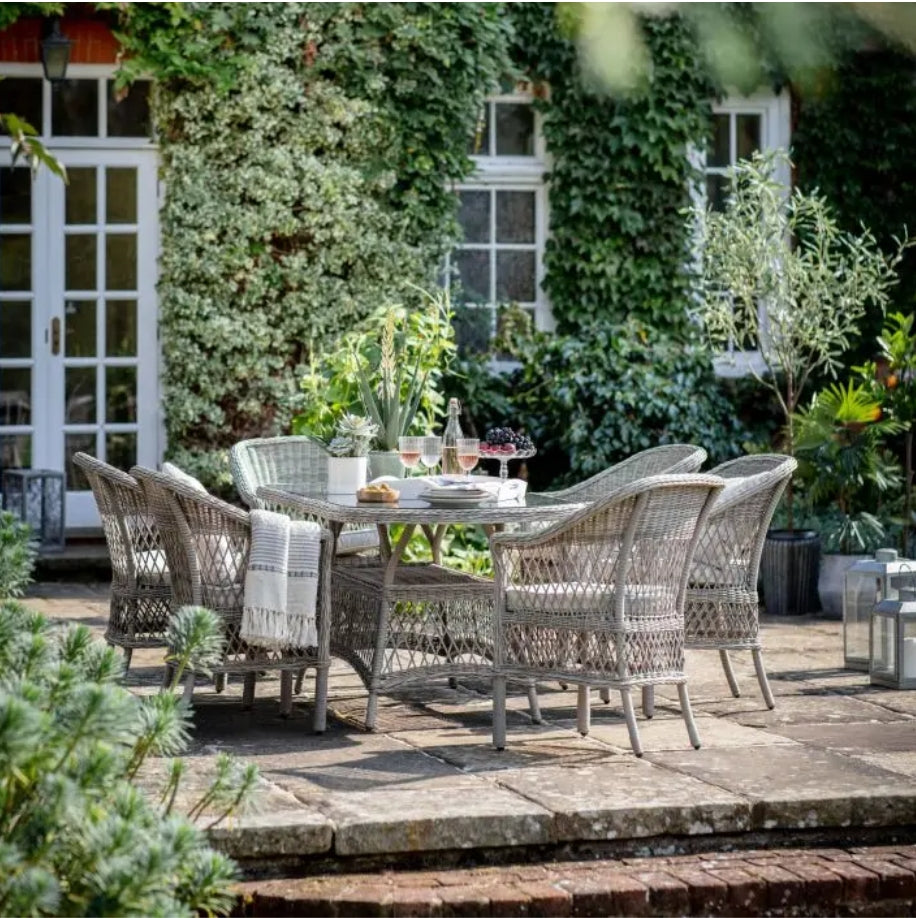 Moreton stone grey colour rattan outdoor furniture, 6 chairs and a glass topped oval dining table with showerproof seat and back cushions, available at Albury House Interiors