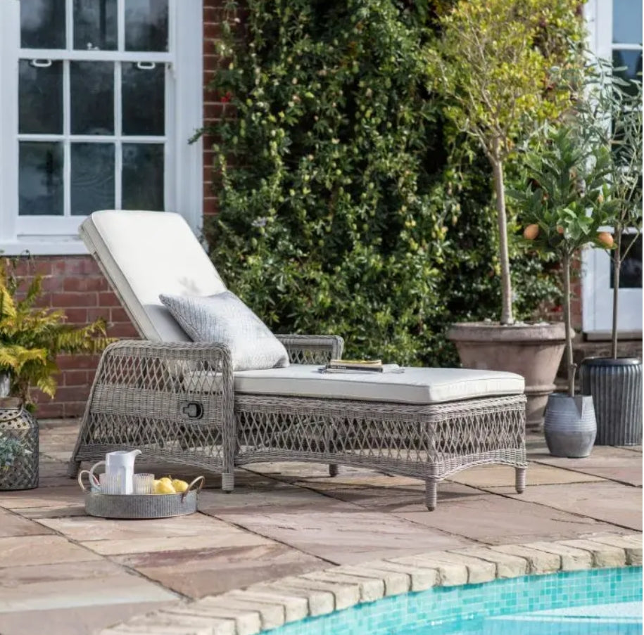 Moreton reclining, all weather, stone coloured rattan lounger with matching weather proof cushions. Pretty open weave rattan, positioned around a pool, available at Albury House Interiors.