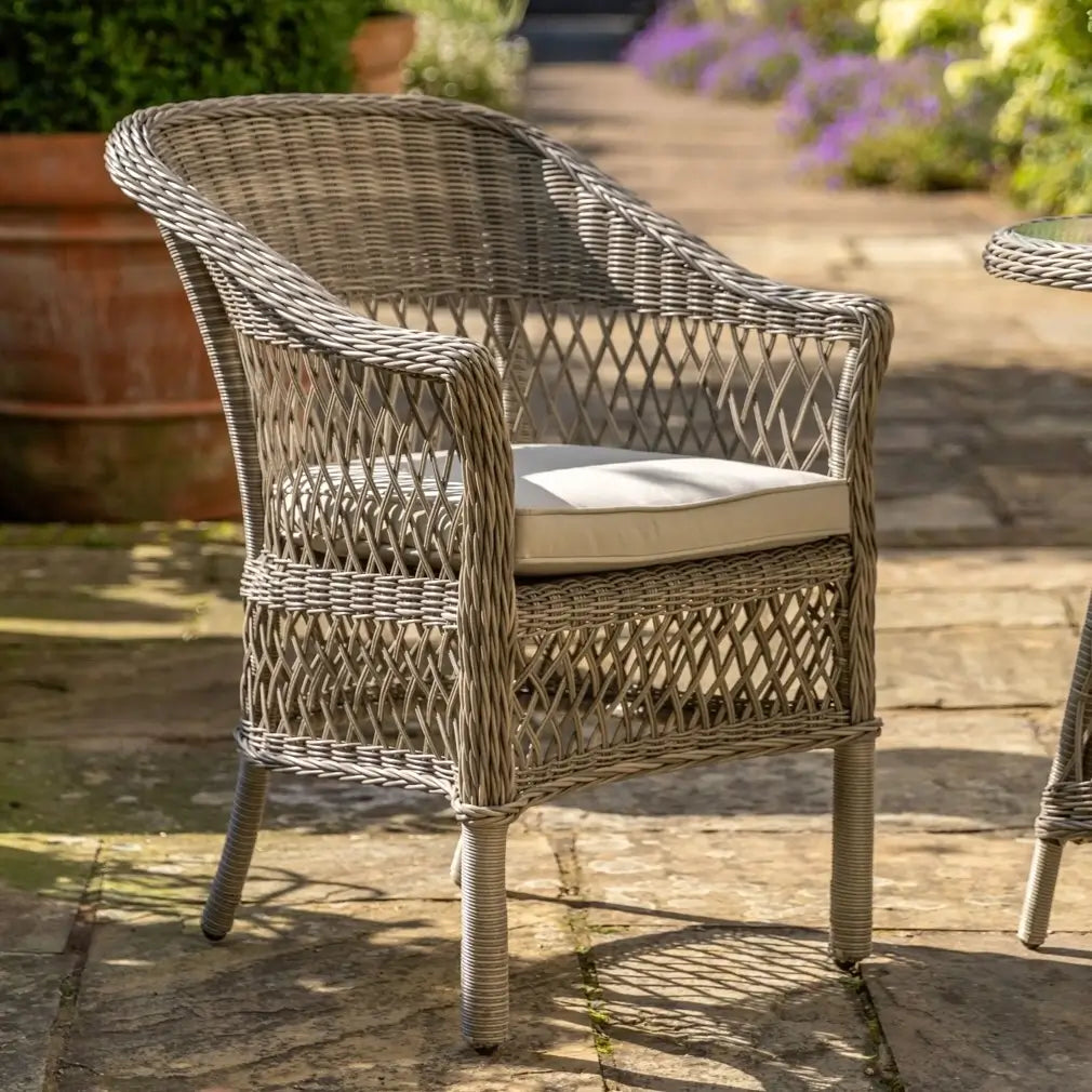 Moreton rattan woven outdoor bistro set with two armchair style seats with natural coloured weatherproof cushions and round rattan glass top table. Available to purchase at Albury House Interiors.