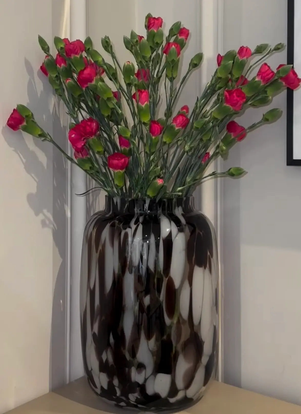 Hand blown brown and white glass oval curved shape vase with mottled, speckled pattern across the entire body, making each one completely unique.This one has been styled with pink carnation flowers. Shop these vases online or in store at Albury House Interiors. 