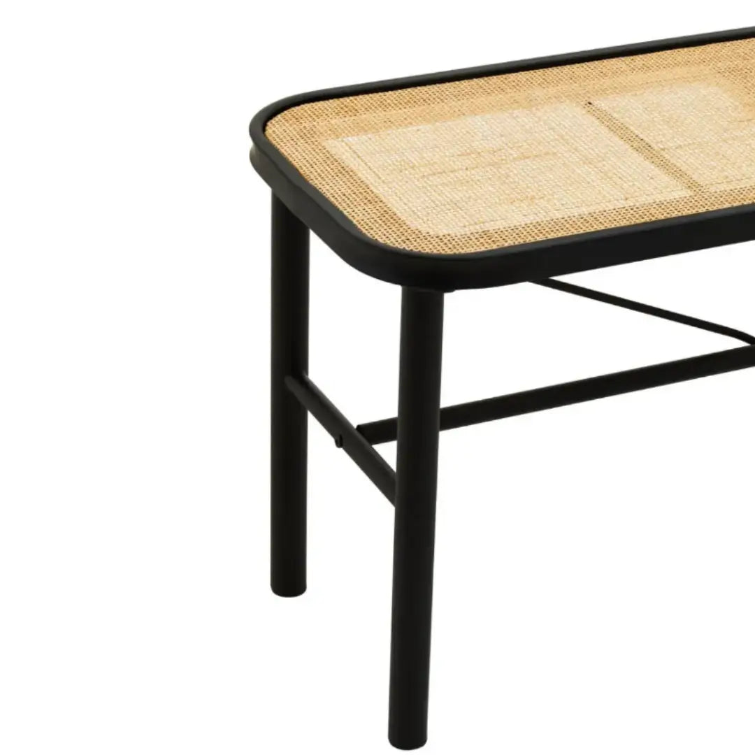 Natural rattan seated bench supported by a black metal frame with tubular legs and a V frame. Available to purchase from Albury House Interiors, Matching Tye Essex. 