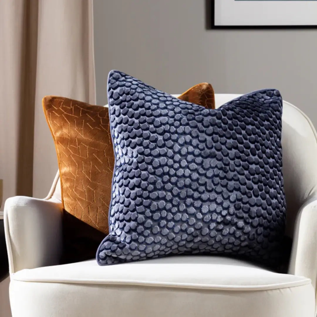 Square navy velvet cushion with bubble effect pattern on front face and plain soft velvet on the reverse side, with matching piped edges. Available at Albury House Interiors, home decor store in Essex.
